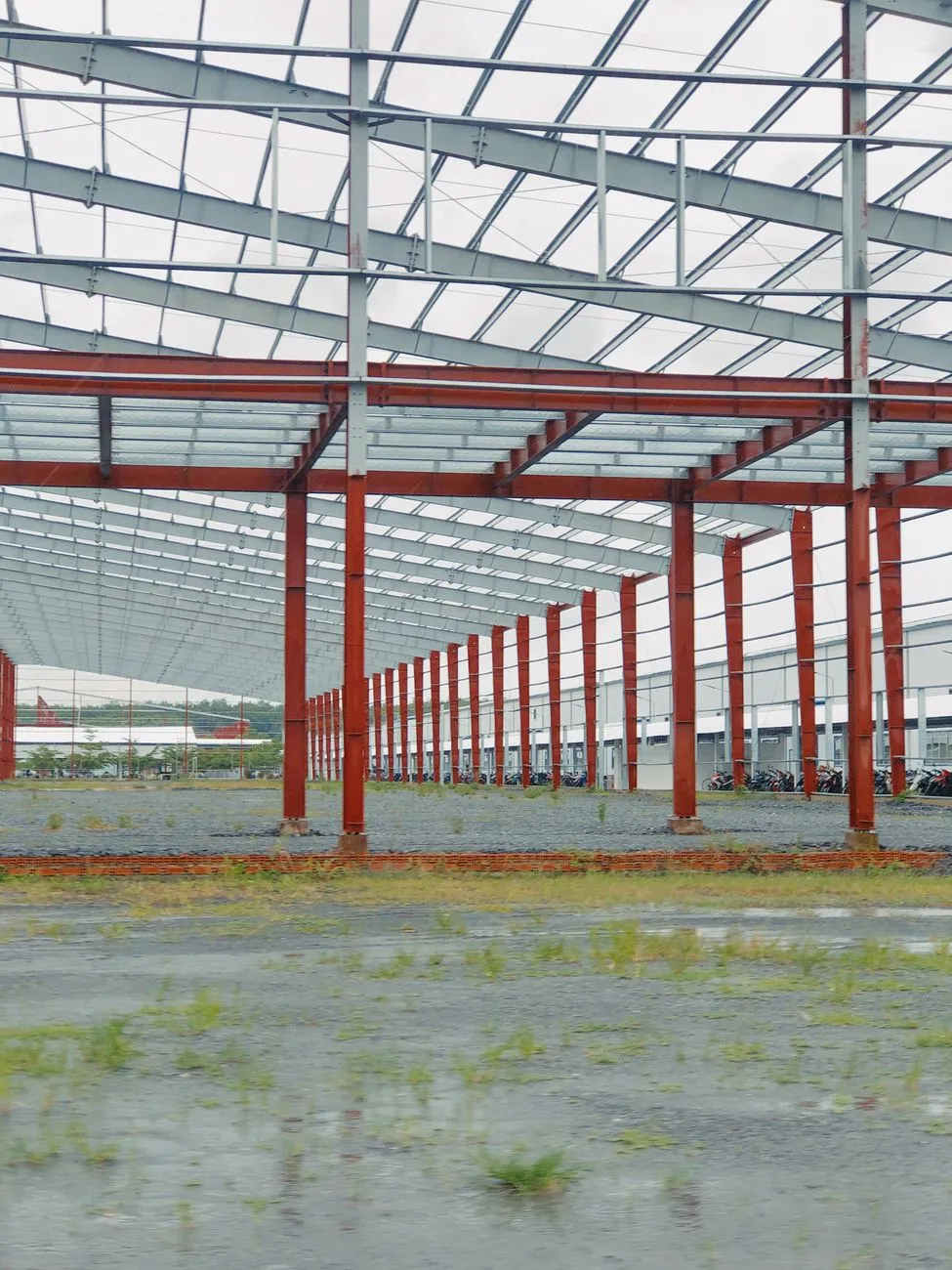 An expansive metal frame structure under construction in an open, industrial space.
